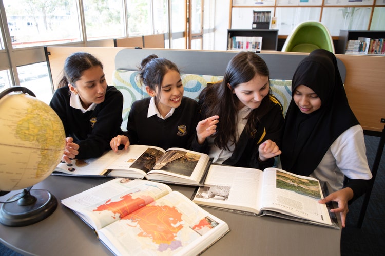 Geography students researching atlas